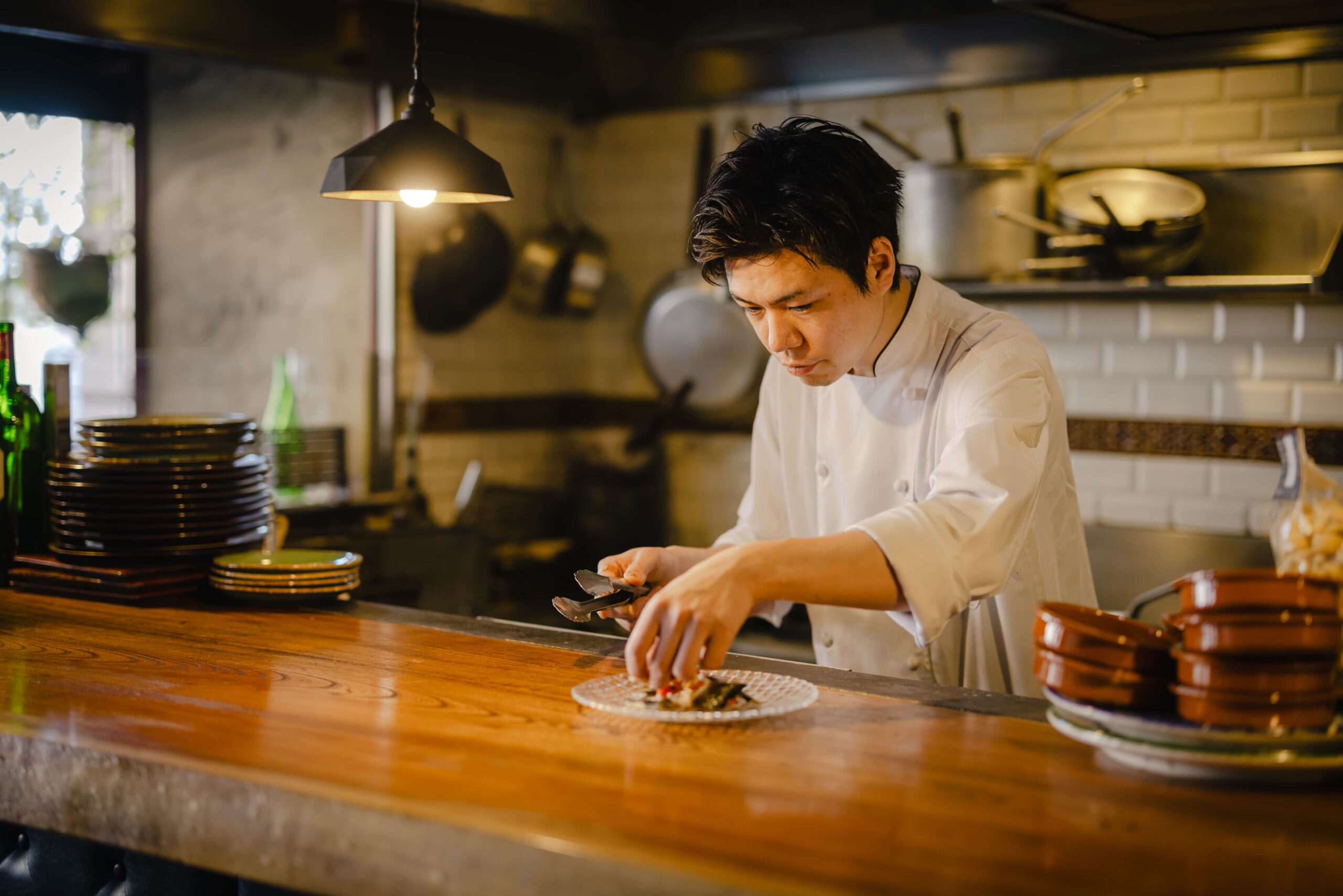 料理の盛り付けをする佐藤シェフ